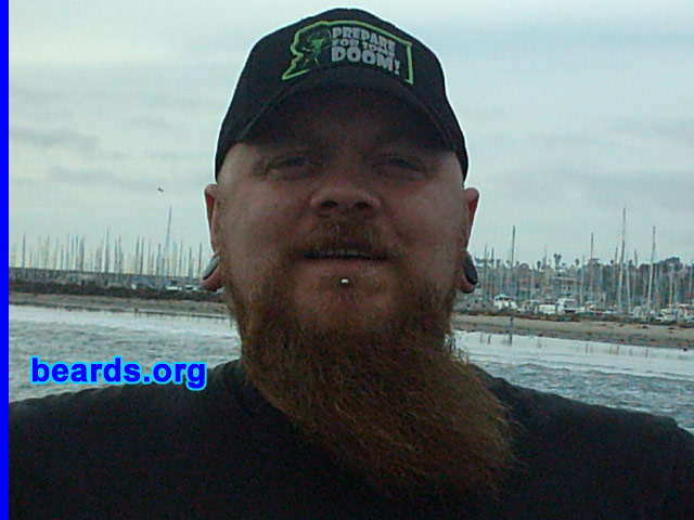 Stumpy
Bearded since: 1990.  I am a dedicated, permanent beard grower.

Comments:
I've grown hair on my chin ever since I could, from around the age of 15, as I have a small pimple/mole which I feel is unsightly. My beard has taken many forms, from full facial, to small goatee, with large sideburns, to what it is today. My hairline began to recede around the age of 20.  As I used to enjoy wearing my hair long, this came as a bit of a setback as the bald, mullet look was definitely not my thing!  So I shaved my head and have kept it shaven ever since. Thus came the experimentation with facial hair! 
-- I see my beard now as a tribute to my good friend Mark, who passed away last year. He had the thickest, most incredible beard known to man! I still have some way to go, but dude, this one's for you!!!

I think my beard is some kind of companion.  It's there when I'm at my desk pondering an issue or problem, it can be stroked in thought and I even have my own beard brush which can be soothing when stressed. Others see it as a conversation piece, asking how long I will grow it.  Or my father will tell me that I have my head on upside down...the usual stuff!  I just really enjoy my beard.
Keywords: full_beard