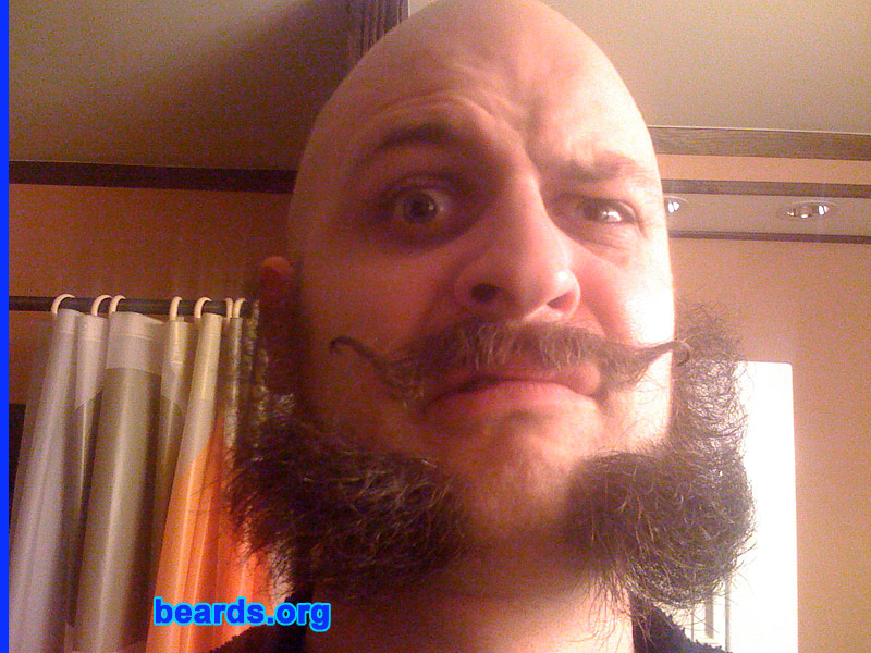 Django
Bearded since: on and off since puberty.  I am an experimental beard grower.

Comments:
I grew my beard because facial hair experimentation is one of my favorite ways to keep people guessing. Folks who only see me once a month, always marvel at how different I look at each encounter. These photos are not quite current. The beard part went away, and now I've got a Dali-worthy mustache only.

How do I feel about my beard?  I love my beard and mustache. In fact, the main reason I shaved my beard was so that I wouldn't keep finding bits of muffin in it. Nearly had a disaster one day, when I found a marble-sized crumb of a recently-eaten pastry hanging out in my facial hair scant minutes before an important business meeting. So it had to go.
Keywords: mutton_chops